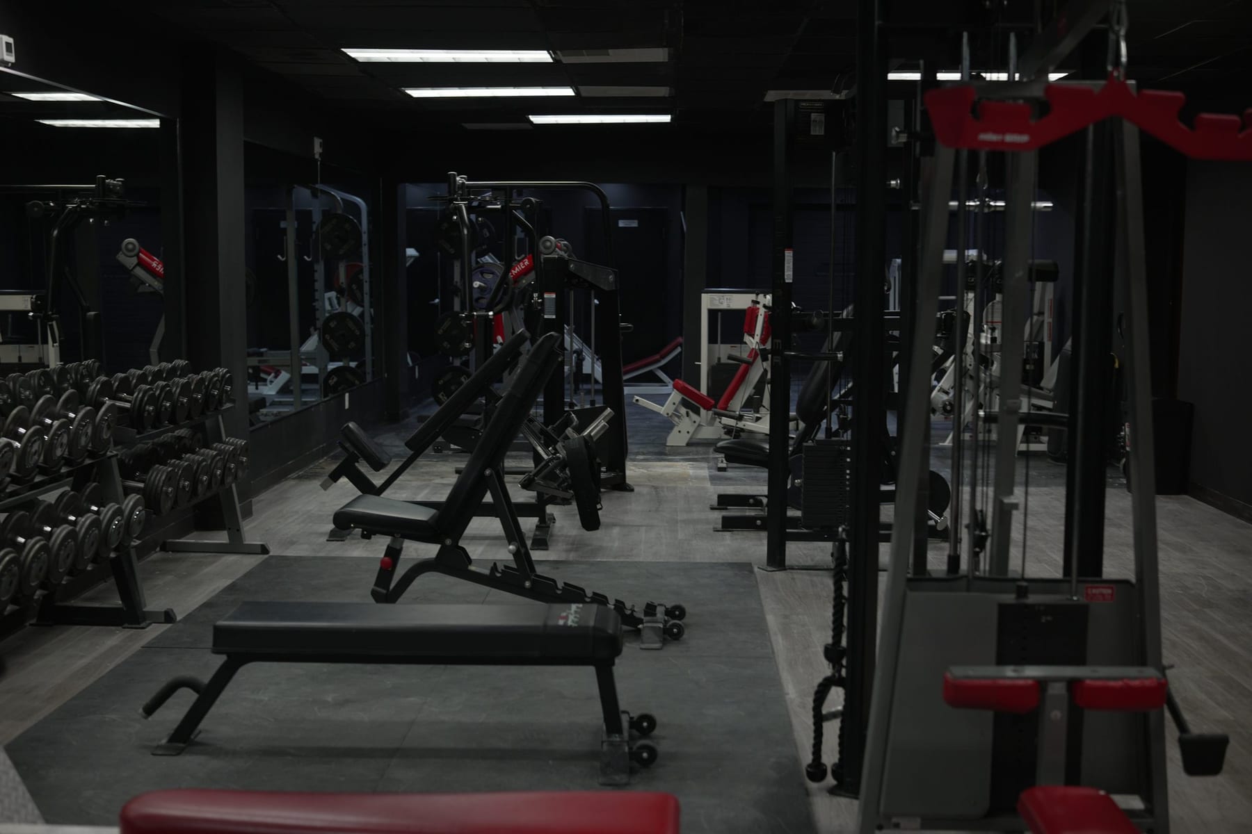 Hadeed's training floor: adjustable benches, cable towers and dumbbell racks under black walls
